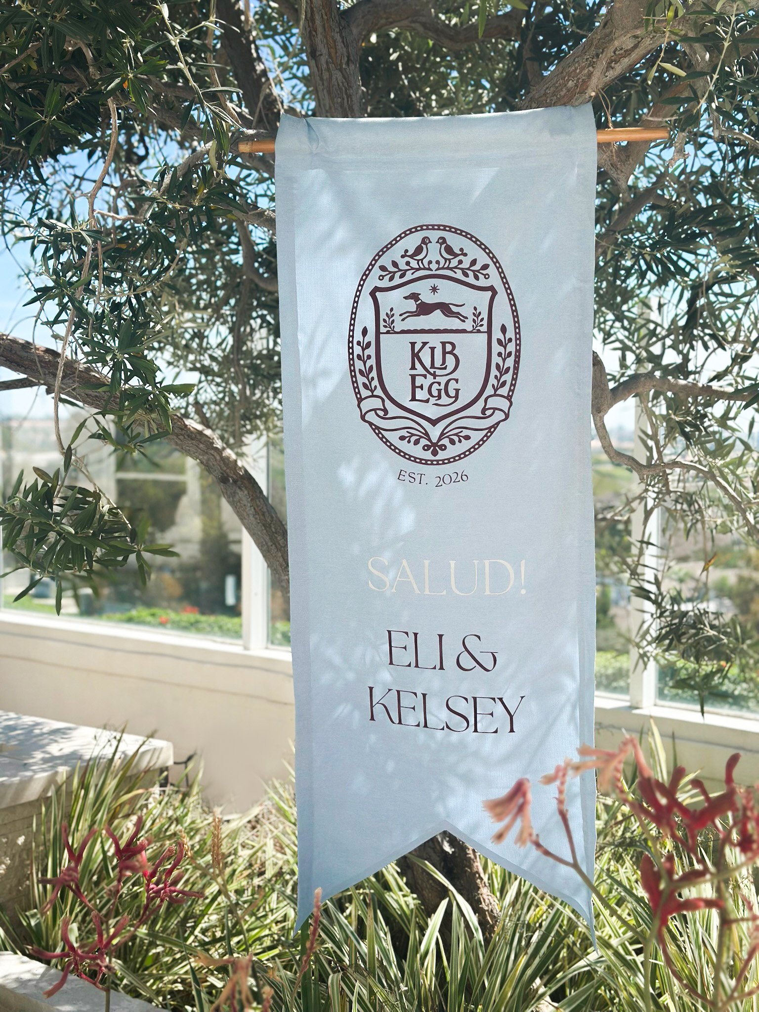 Custom made fabric banner with family crest hanging from a tree for a couple getting married